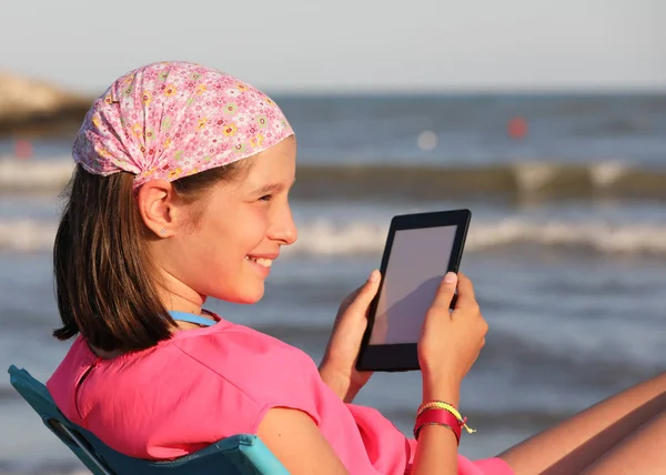 Fille lit un livre numérique sur la rive — Photo