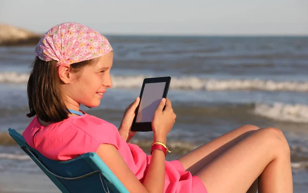 Jolie petite fille lit un ebook sur la plage — Photo