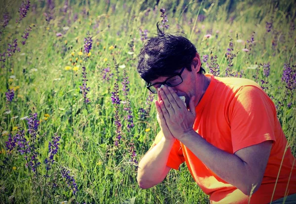 Menino com camisa laranja espirra porque alergia — Fotografia de Stock