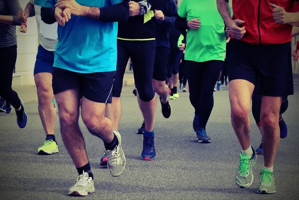 Pernas de corredores durante uma corrida com efeito tonificado velho — Fotografia de Stock