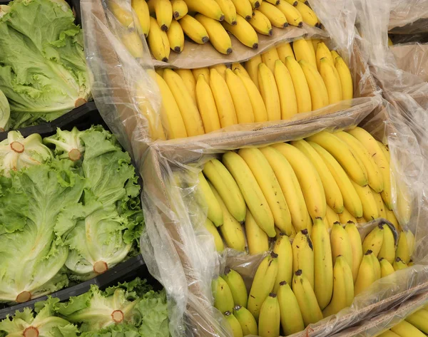 Полные коробки зеленого свежего салата и желтых бананов — стоковое фото