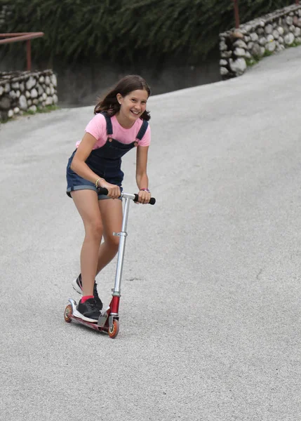 Fast little girl on scooter with dungarees — Stock Photo, Image