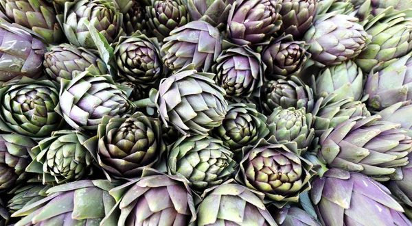 Achtergrond van groene rijpe artisjokken te koop op de markt — Stockfoto