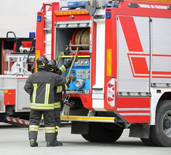 Carro de bombeiros e dois bombeiros — Fotografia de Stock