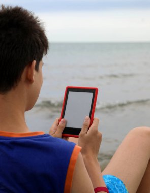 Genç çocuk yaz aylarında sahilde ebook okur