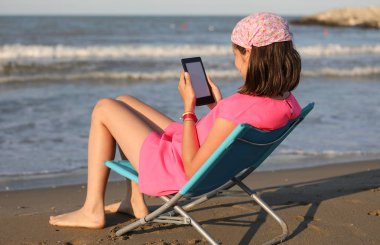 kız denize bakan bir dijital kitap okur