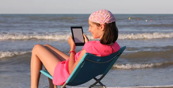 Petite fille avec bandana rose lire un ebook — Photo