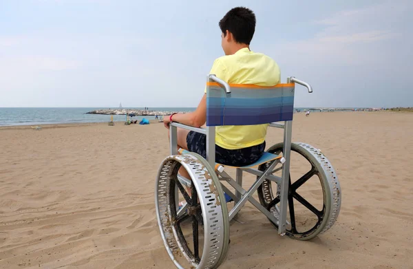 Samotnie młody chłopak na wózku inwalidzkim na plaży — Zdjęcie stockowe