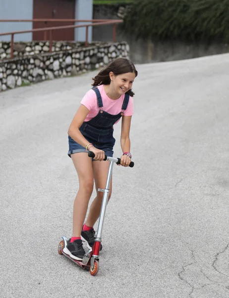 Fast little girl on scooter with dungarees jeans — 스톡 사진