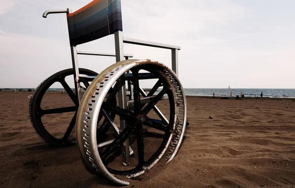 Cadeira de rodas com roda na praia com efeito tonificado escuro — Fotografia de Stock