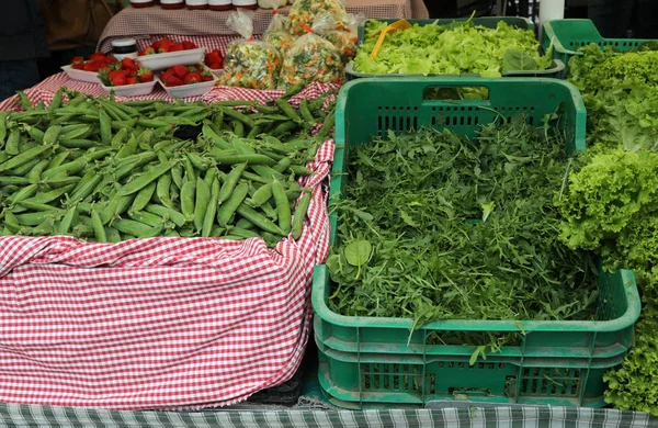 Many green peas and fresh rocket arugula for sale — Zdjęcie stockowe