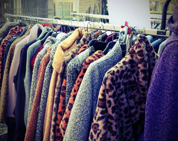 Vestiti e pellicce appesi al mercato bancarella con vecchio effetto tonico — Foto Stock
