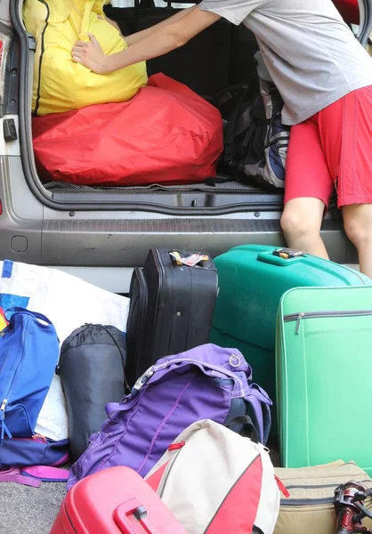 Мальчик загружает багажник автомобиля с большим багажом — стоковое фото