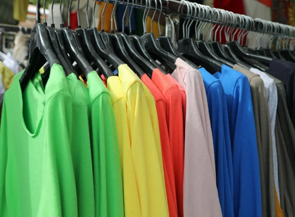 Camisas de colores colgando en la percha para la venta en la tienda —  Fotos de Stock