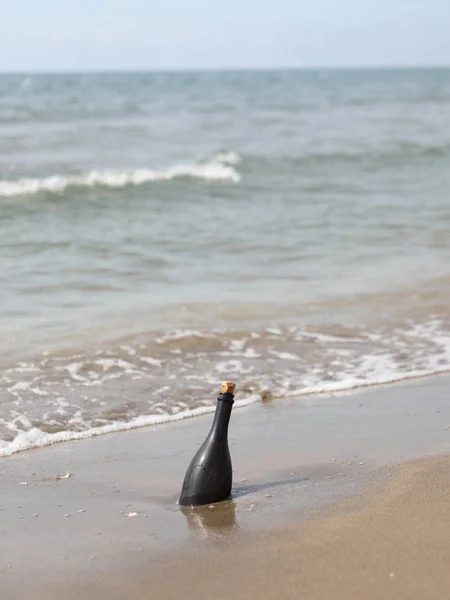 Glass bottle  transported from the waves to the shore — Stock Photo, Image
