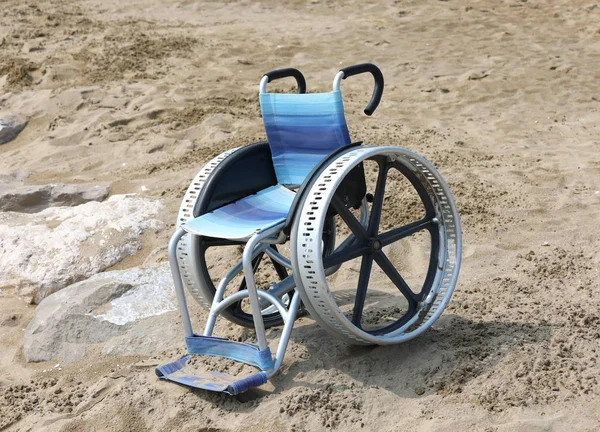 locked wheelchair with large aluminum wheels on th sandy beach