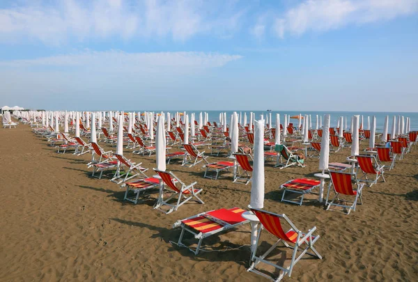 Sun umbrellas with deckchairs on the beach without people in the — Stock Photo, Image