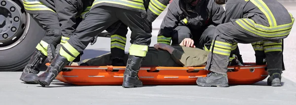 Feuerwehrleute legen eine verletzte Person auf eine Trage — Stockfoto