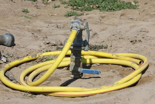 Gelbe Schlauchleitung auf dem sandigen Boden — Stockfoto