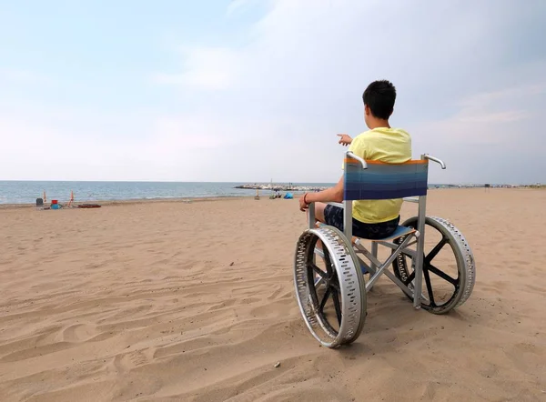 Młody chłopiec w żółtej kamizelce na wózku inwalidzkim — Zdjęcie stockowe