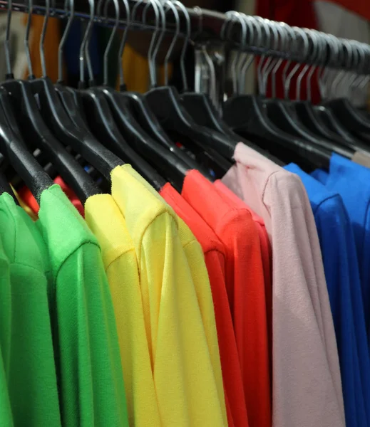 Mnoho barevných košil visí na ramínku na prodej — Stock fotografie