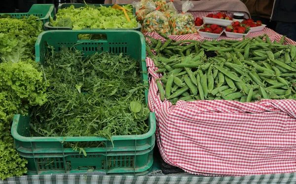 Doos van verse groene raket arugula en erwten te koop op stand — Stockfoto