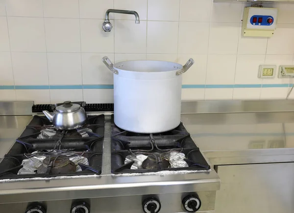 large aluminum saucepan in the industrial kitchen and the tap for filling with water above the stove