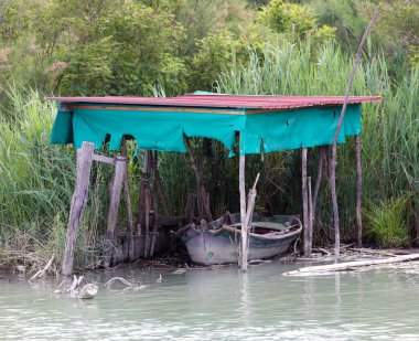 Nehir kıyısında terk edilmiş eski bir balıkçı köyü ve eski bir tekne.