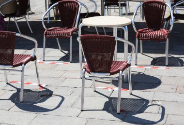 Corona Virüsü tarafından empoze edilen sosyal mesafeyi sınırlamak için tabelaların olduğu Alfresco kafe masaları