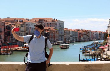 Young man with surgical mask on Rialto Bridge in Venice in Italy