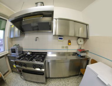 industrial kitchen photographed with fisheye lens without the cooks with stove and stainless steel furniture clipart