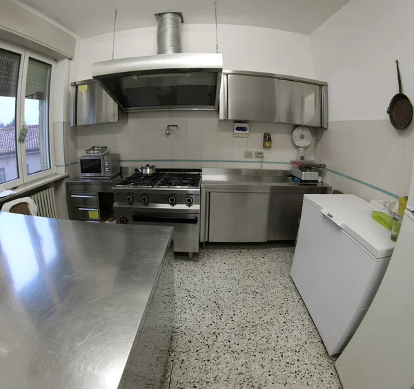 large interior of industrial kitchen with stainless steel stove and large extractor hood without cooks