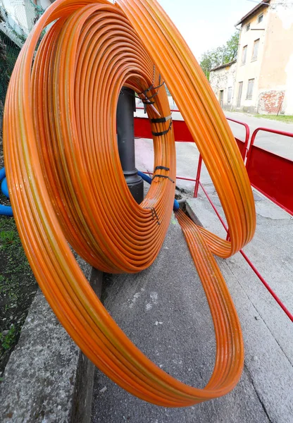 Orange piping in the road construction site for the laying of the fiber optic infrastructure to bring high-speed internet to the homes — Stock Image Orange Piping Road Construction Site Laying Fiber Optic Infrastructure Bring Royalty Free Stock Images