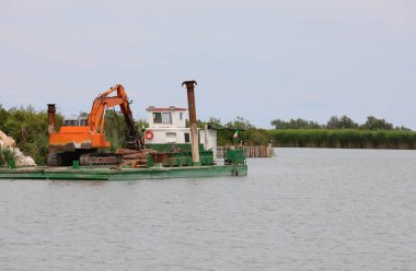 barge on the river with a large digger for construction work on the shore
