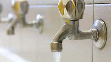 Suyun akışını engellemek için eski bir musluğu kapatan adamın eli