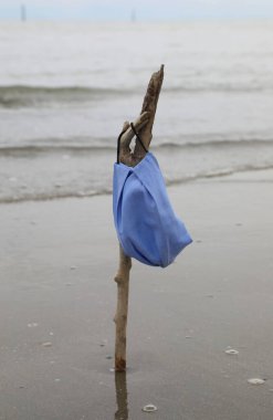 Enfeksiyonun sona erdiği yaz mevsiminin ardından deniz kenarındaki bir dalda cerrahi maske takıldı.