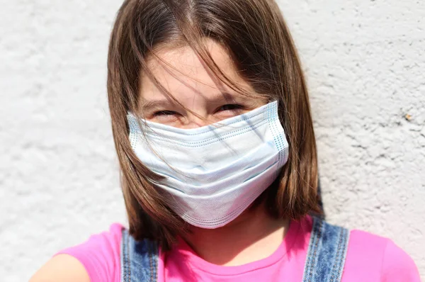 笑顔目の女の子とともに外科マスクのために保護へCovid 19とともに茶色の髪吹いて風 — ストック写真