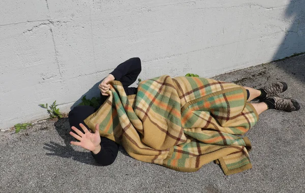Молодой Бездомный Лежит Улице Асфальте Старым Одеялом Рука Поднята Защитить — стоковое фото