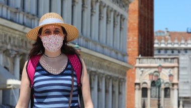 Cerrahi maskeli ve hasır şapkalı güzel bir kadın tecrit sırasında İtalya 'nın Venedik kentindeki Saint Mark Meydanı' na turist ziyaretinde