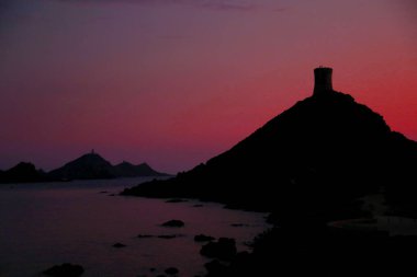 silhouette of the sanguinary islands near the city of Ajaccio in Corsica during the red sunset and a lookout tower clipart