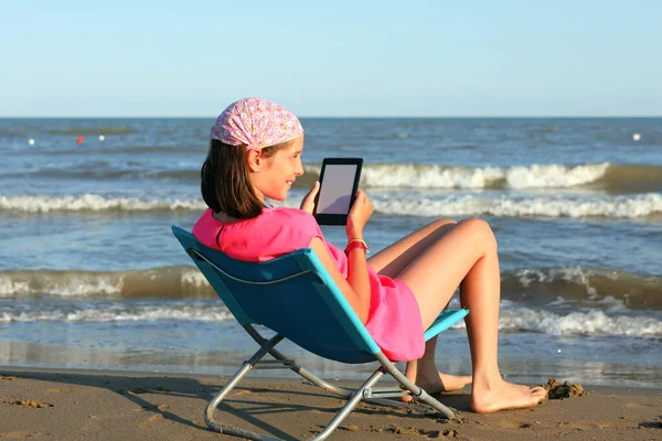 Mała Dziewczynka Leżąca Brzegu Morza Czytając Elektroniczny Tekst Booka — Zdjęcie stockowe