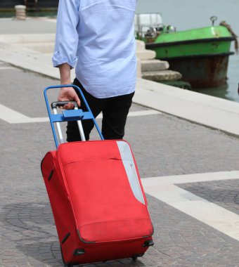 İtalya 'da Venedik adasında yürürken kırmızı bavullu turist