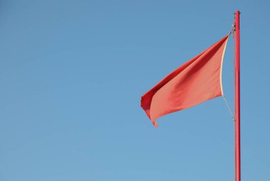 red flag indicating a dangerous situation on the background of the blue sky clipart
