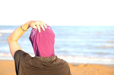 Yazın deniz kıyısında duvağı olan Arap kadının eli çok aydınlıktı.