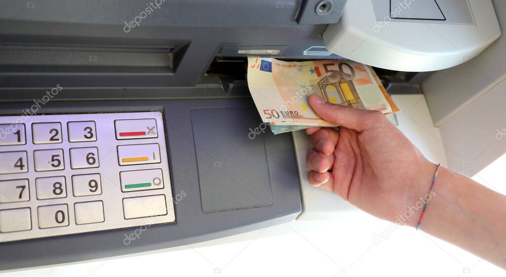 person withdrawing money in European banknotes from an ATM