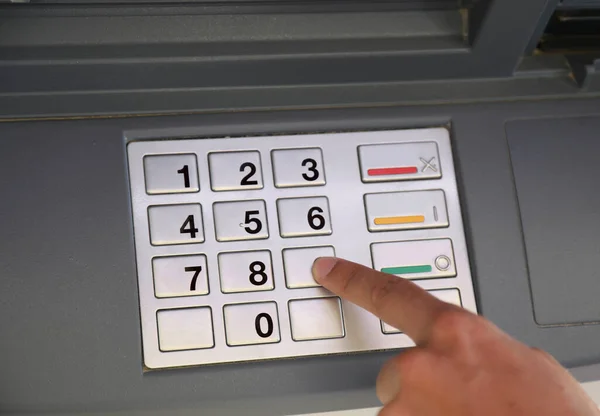 person typing the secret code into the ATM machine keyboard