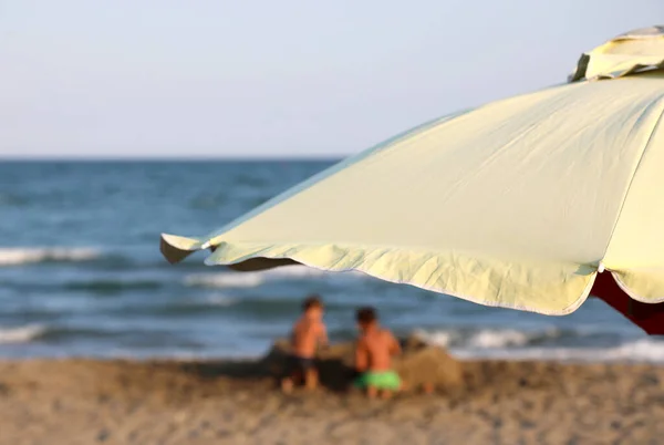 注意力不集中的孩子们在海边和大雨伞旁玩耍 — 图库照片