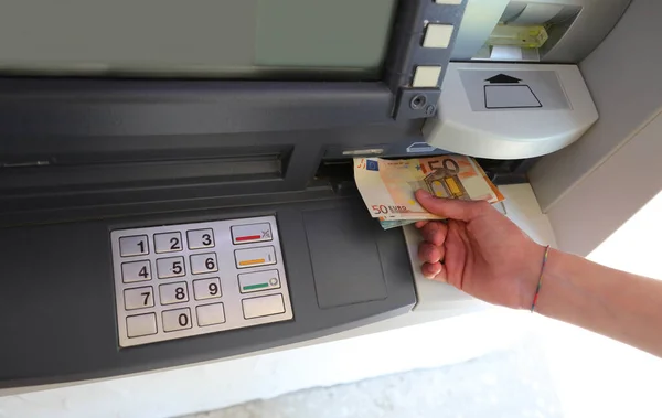 ATM cash machine with keyboard and hand picking up European currency banknotes
