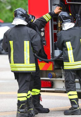 İtfaiyecilerden oluşan bir ekip acil bir durumda itfaiye araçlarını alıyor.