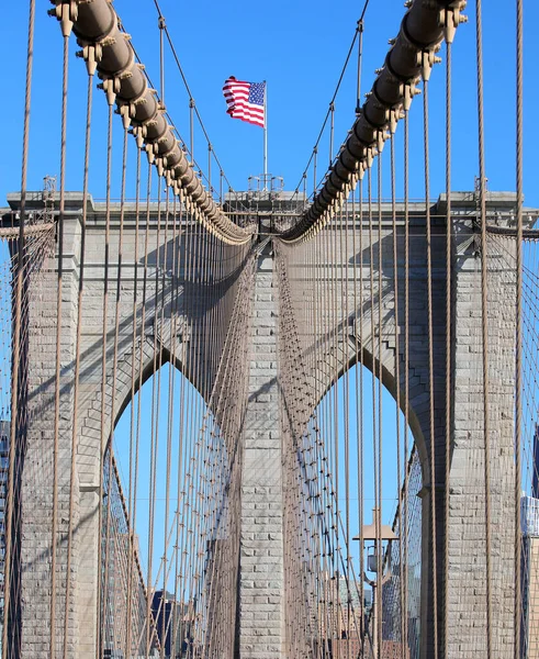 Brooklyn Köprüsü 'nün tepesinde büyük Amerikan Bayrağı ve New York' ta çelik kablolar ve güneşli bir günde mavi gökyüzü.